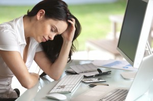 Financial Setbacks: Woman looking stressed at her desk, eyes closed