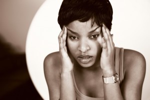 Young lady with distressed look holding head, in hands; horizontal sepia toned format 